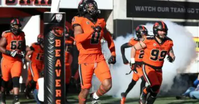 Oregon State football player run onto the field from the tunnel.