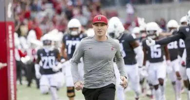 Washington State football coach Jake Dickert runs on the the field with his team