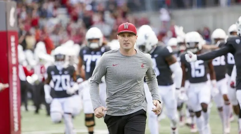 Washington State football coach Jake Dickert runs on the the field with his team